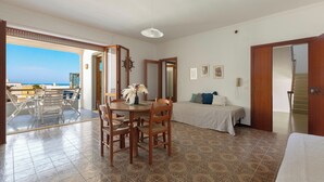 A room with a balcony, a dining area, a bed, and a staircase. - Balconcino Vista Mare by BarbarHouse (San Foca)