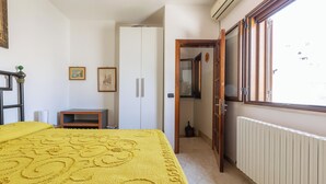 Een slaapkamer met een bed, een kledingkast, een radiator en een raam.