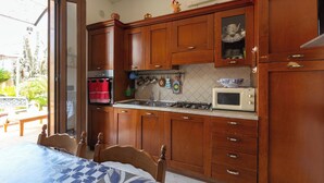 Een keuken met houten kastjes, een magnetron en een gasfornuis.