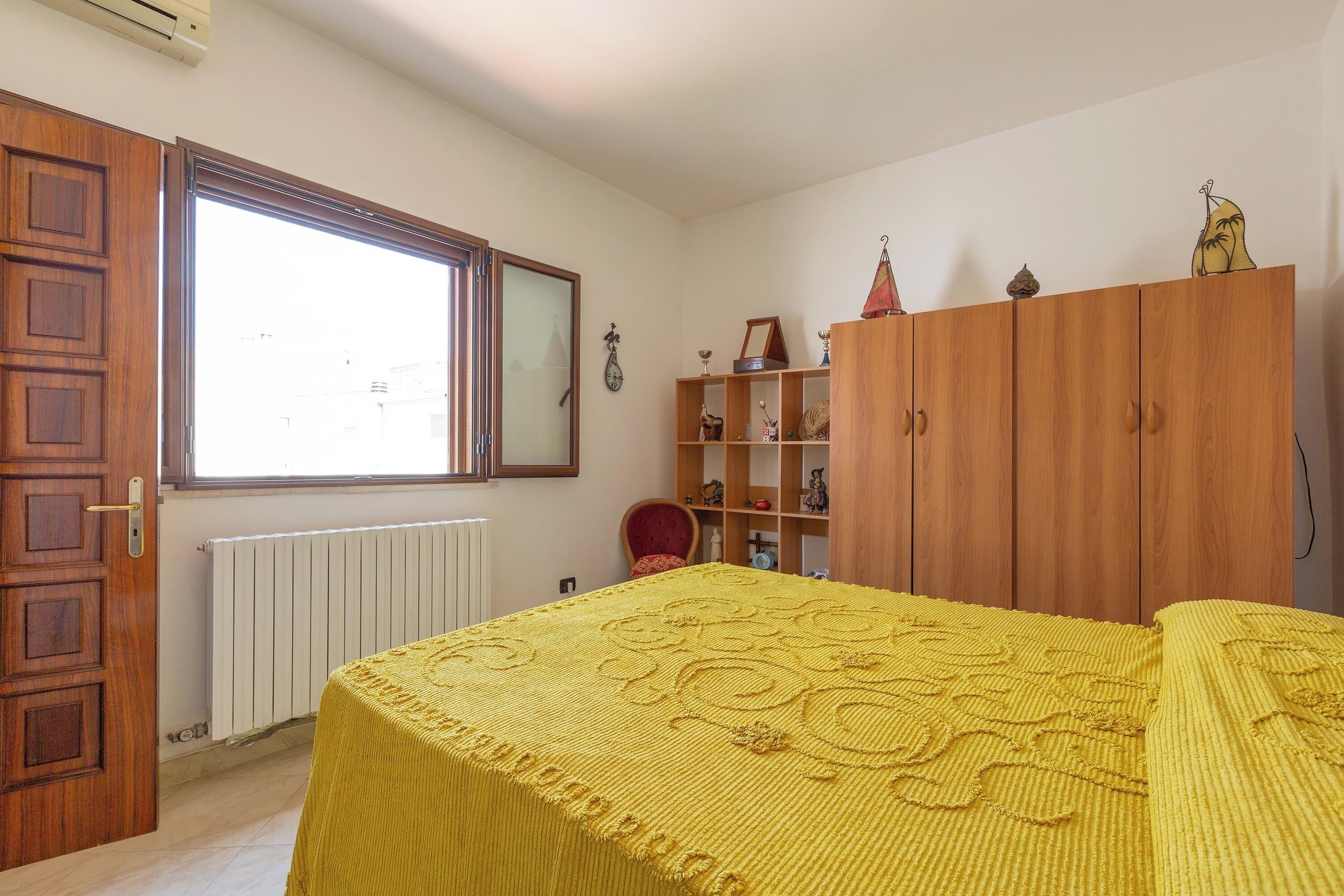 Une chambre à coucher avec un lit, une armoire en bois, un radiateur et une fenêtre.