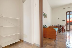 Ein Zimmer mit einem Bett, einer hölzernen Bank, einem Esstisch mit Stühlen und Blick durch eine Glastür.