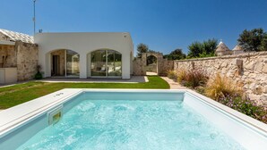 A modern house with a swimming pool, stone walls, and a clear blue sky. - Trullo Pumo by Perle di Puglia (San Michele Salentino)