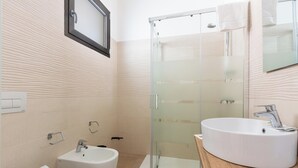 Een moderne badkamer met een douchecabine van glas, een wastafel en een toilet.