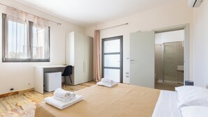 Een hotelkamer met een bed, bureau, stoel, douche en kledingkast.