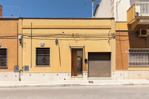 Ein Gebäude mit gelber Fassade, einem geschlossenen Rolltor und einem kleinen Fenster mit Metallgitter.