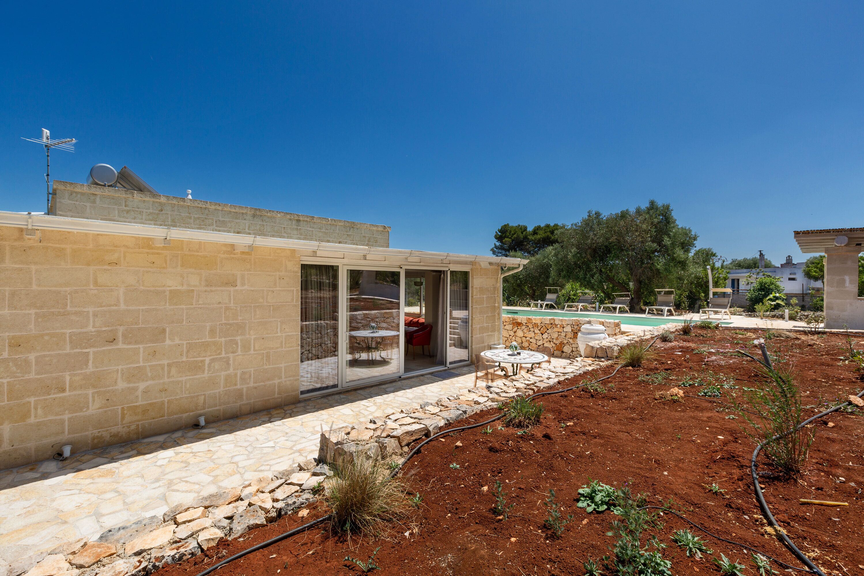 A modern house with a patio, a swimming pool, and a garden.