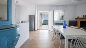 Une cuisine moderne avec un plan de travail bleu, un coin repas blanc avec des chaises et un téléviseur fixé au mur.