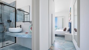 Een moderne badkamer met een douchecabine van glas, een witte wastafel en een vloer betegeld met marmer.