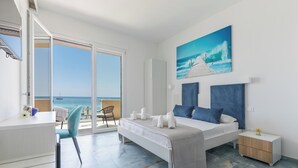 Een moderne slaapkamer met een groot bed, een bureau en een stoel. Er is uitzicht op de oceaan door een schuifdeur.