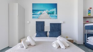 Hotelkamer met een bed, een schilderij van een pier die naar golven leidt, een nachtkastje en een blauwe plank.