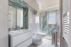 Ein modernes Badezimmer mit großem Spiegel, Waschbecken, Bidet und Duschbereich.