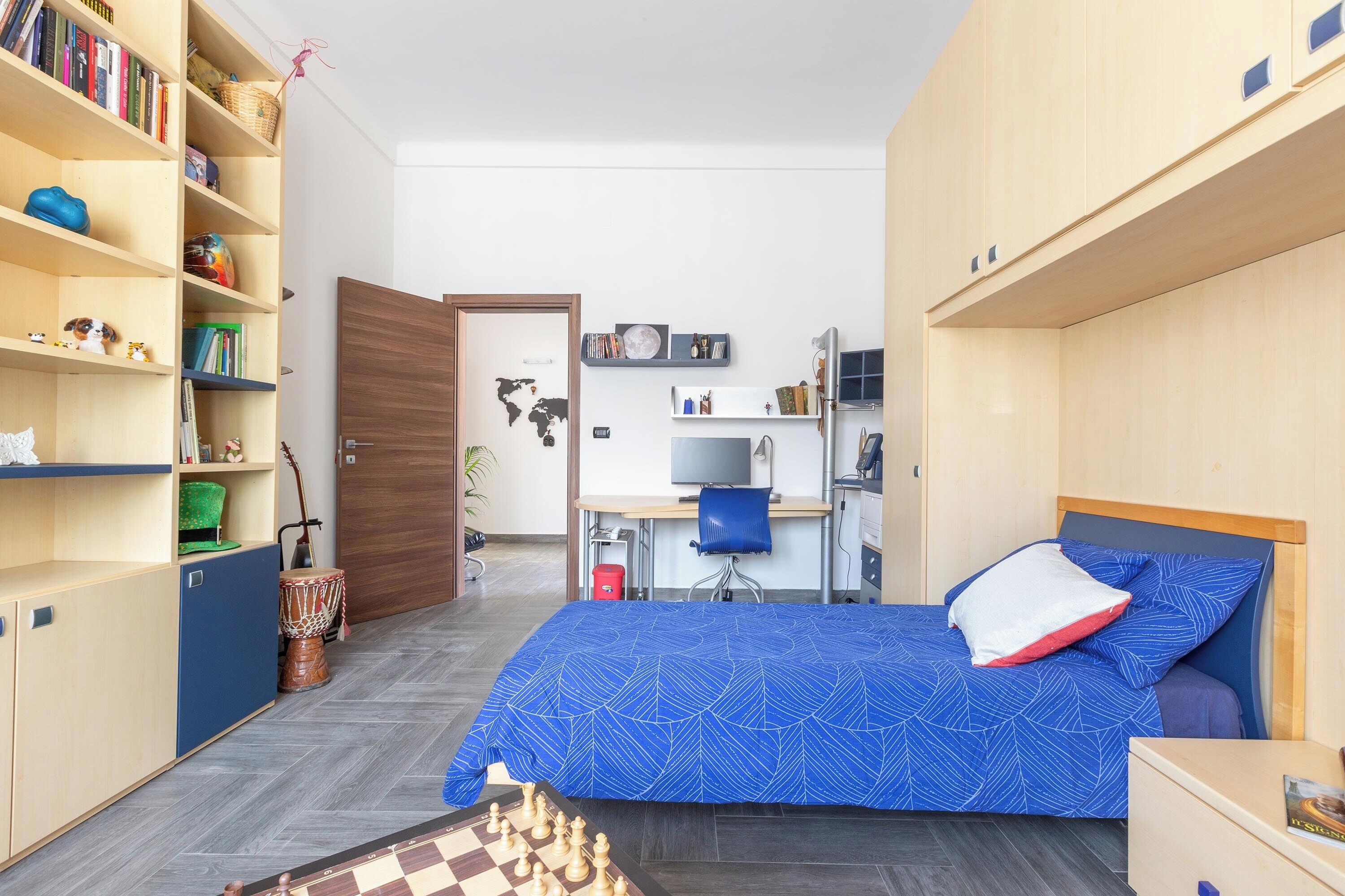 A compact room with a bed, a desk, and a bookshelf.