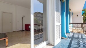 Een interieur met een schuifglazen deur naar een balkon, een rode bank en een vloerlamp.