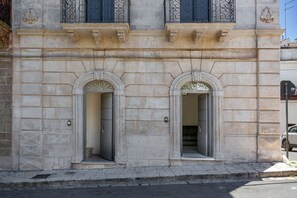 A building facade with two arched doorways, stone walls, and decorative metalwork. - Alemar Appartamento con SPA by Perle di Puglia (Carovigno)