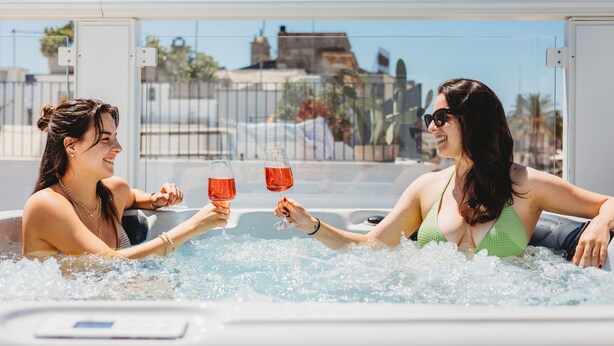 Deux personnes dans un jacuzzi, avec une vue dégagée sur l’extérieur.
