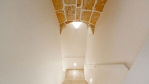 Un escalier surmonté d’une arche en pierre menant à un palier.