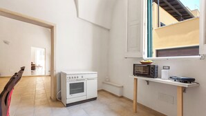 Una cocina compacta con horno blanco, microondas y una pequeña mesa.