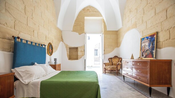 Un dormitorio con cama, cómoda, silla y un cuadro en la pared.