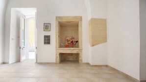 Un pasillo con chimenea, una puerta que da a otra habitación y suelo de baldosas.