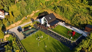 An aerial view of a property with a large lawn, a tennis court, and a building with a sloped roof. - A Comfortable House in Kashubia for 7 People (gmina Stężyca)