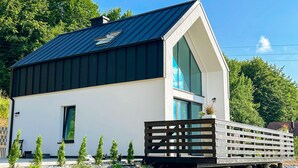 Una casa moderna con tetto spiovente, un'ampia finestra e un piccolo portico.