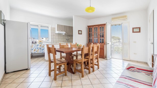A spacious kitchen with a dining table and chairs, a refrigerator, and a yellow pendant light. - Casa Sapore by BarbarHouse (San Pietro in Bevagna)