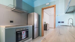 Une cuisine moderne dotée d’un four encastré, d’un réfrigérateur en acier inoxydable et d’un plan de travail en bois.