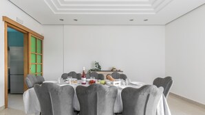 Un coin repas avec une table ronde, des chaises à revêtement gris et une nappe blanche.
