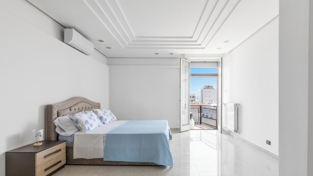 Une chambre à coucher avec un lit, une table de chevet et une vue sur l’extérieur.