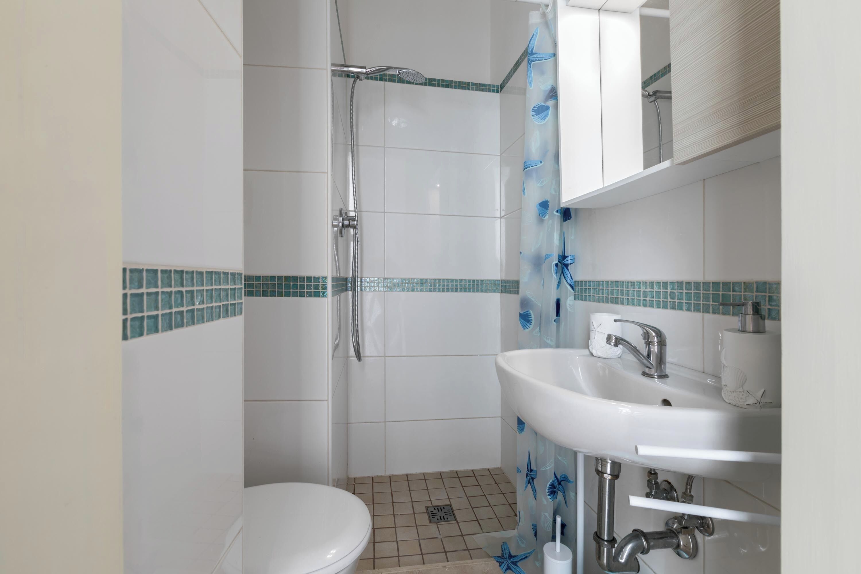 A bathroom with a shower, toilet, and sink.