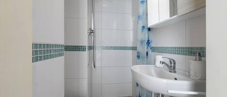 A bathroom with a shower, toilet, and sink.