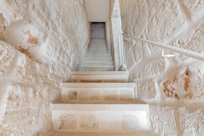 Eine enge Treppe mit weißen Stufen, die nach oben führt, umgeben von strukturierten Wänden.