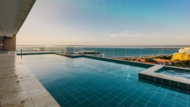 Une piscine à débordement située sur le toit, avec une eau d’un bleu cristallin, une vue sur la mer et une île qui se dessine à l’horizon.