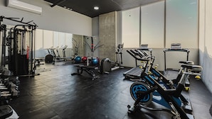 Une salle de sport équipée de divers appareils d’entraînement, notamment des tapis de course, des appareils de musculation et des poids libres.