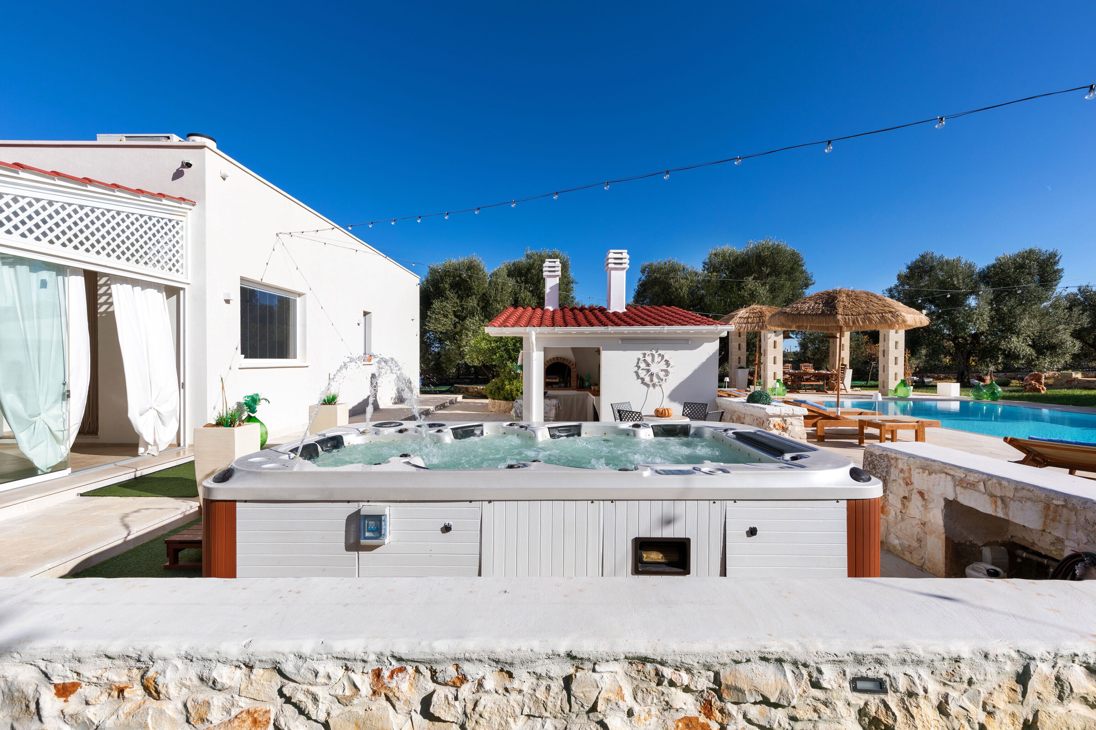 Uma área de hidromassagem com parede de pedra, pérgola e piscina.