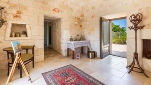 Una habitación con paredes de piedra, una chimenea, una mesa con mantel de encaje y una alfombra.