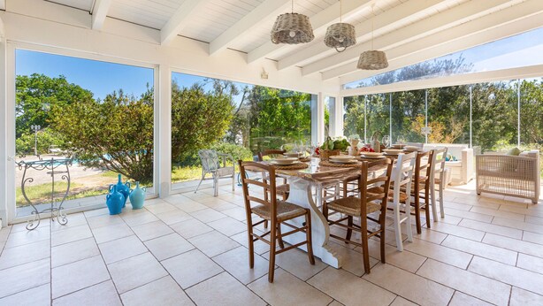 Un patio techado con una mesa de comedor, sillas y lámparas de mimbre colgantes.