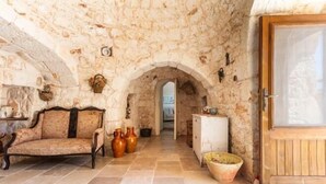 Una habitación con paredes de piedra, un sofá, jarrones y una puerta de madera.