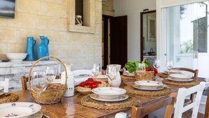 Una mesa de comedor dispuesta con platos, vasos y una cesta de fruta.
