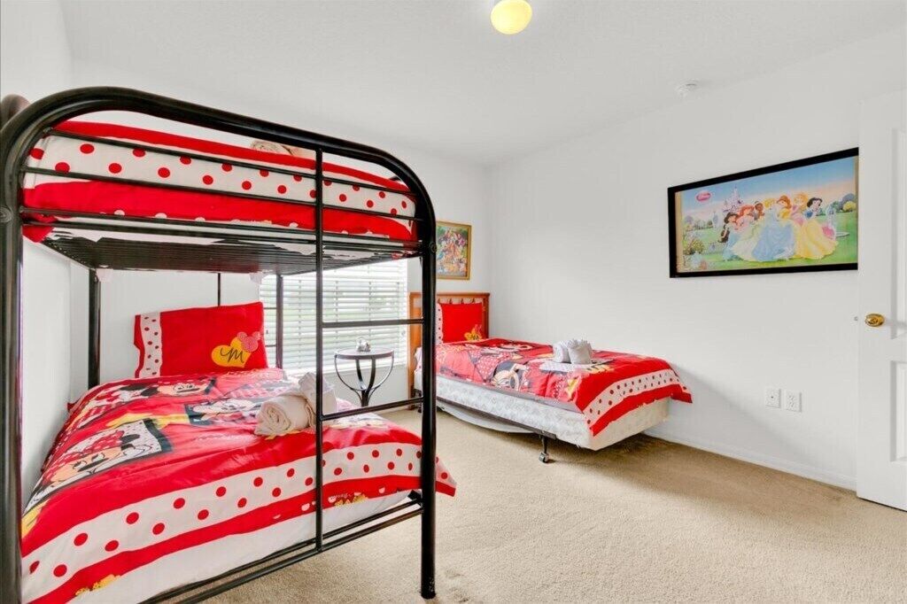 Una habitación con literas, una mesita pequeña y un cuadro en la pared.