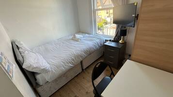Una habitación pequeña y ordenada con una cama individual, un escritorio y una silla.