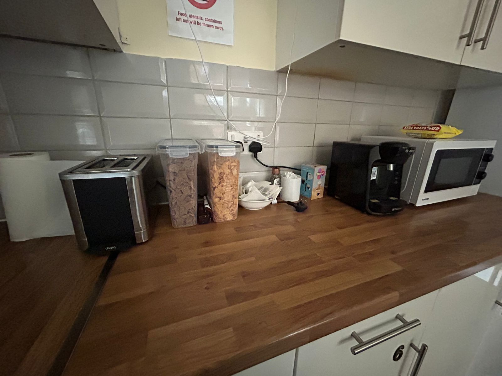 Une cuisine équipée d’un grille-pain, de deux récipients contenant de la nourriture, d’une machine à café et d’un four à micro-ondes.