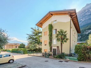 A multi-story building with a sloped roof, surrounded by greenery and a mountainous backdrop. - Ca dei Noni by Interhome (Riva del Garda)