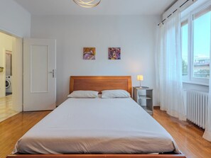 Un lit bien fait dans une chambre d’hôtel, avec une tête de lit en bois, une lampe de chevet et deux tableaux accrochés au mur.