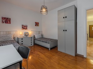 A bedroom with a bed, bedside tables, a desk, a wardrobe, and a hanging light fixture. - Ca dei Noni by Interhome (Riva del Garda)