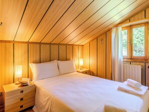 Ein Schlafzimmer mit Holzwänden, einem Bett, Nachttischlampen und einem Fenster mit Vorhängen.