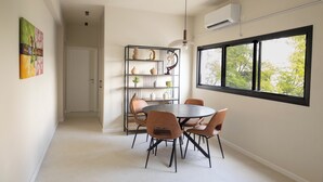 Comedor con una mesa redonda, seis sillas, una lámpara colgante y una estantería decorada.