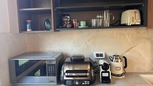 Una cocina equipada con microondas, tostadora, cafetera y diverso menaje.