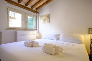 Ein Hotelzimmer mit einem Bett, zwei Fenstern, einer Heizung und einem Wandbild.