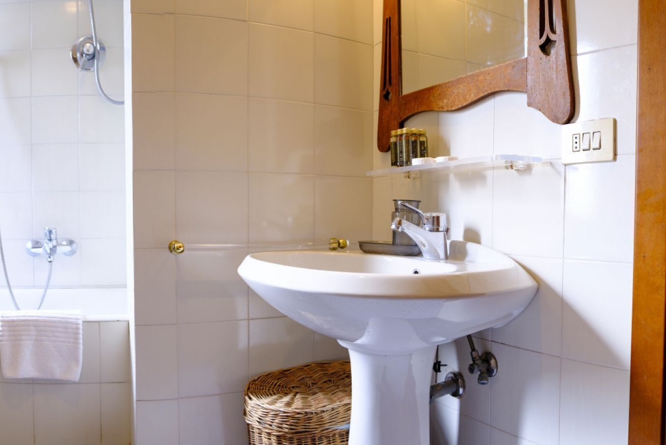A bathroom with a white sink, a mirror, and a shower.